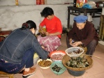 Folding bambo leaf wrappers around rice and meat to make zong zi